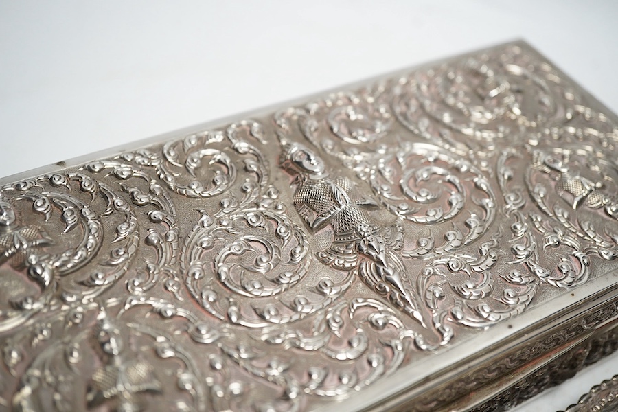 A Thai white metal cigarette box, wood lined, stamped Thainakon, 20cm and a Ceylonese white metal dish, shaped in the form of the country, with embossed borders, and inscription, maker’s mark SS, 24.7cm long, 182g. Condi